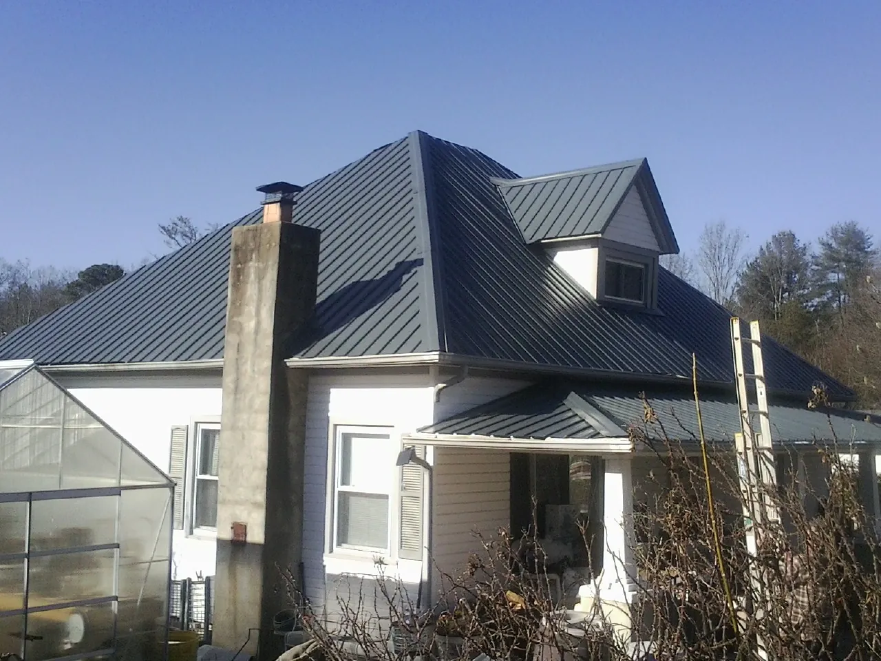 Dark blue standing seam metal roof on a white farmhouse with dormer — Slate & Tile Roof Repair by Roofing Brothers in Kirkville