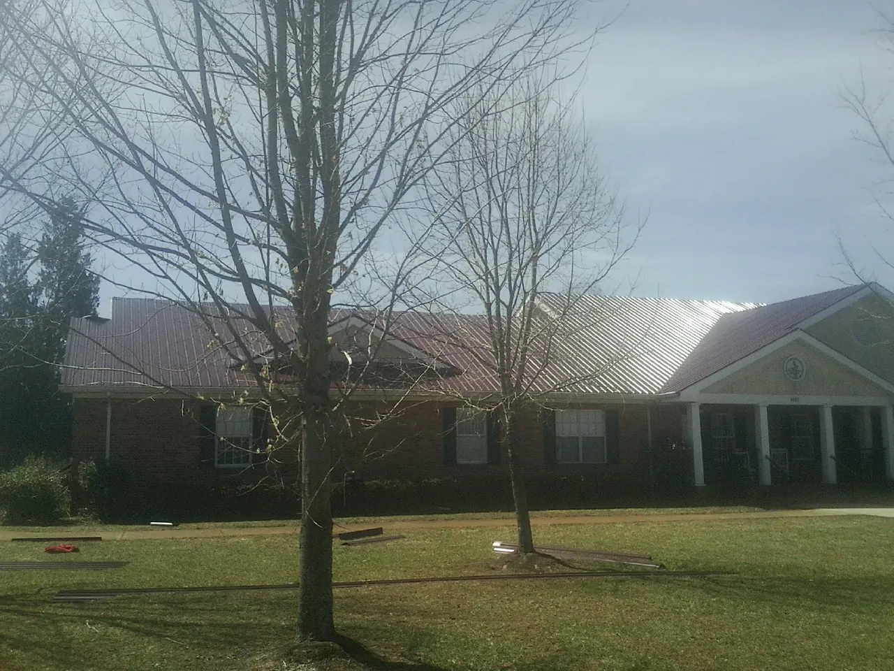 Red metal roof on a brick building seen from the front lawn in Kirkville
