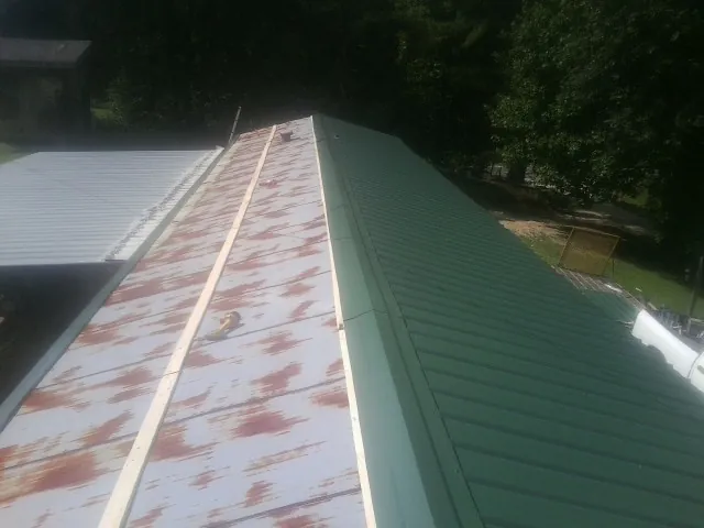 Old rusted panels beside newly installed green metal roofing — Wind Damage Roof Repair by Roofing Brothers in Kirkville