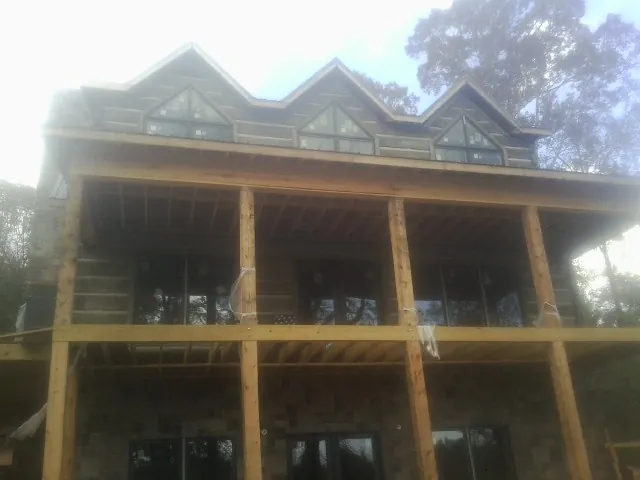 Dormers and porch framing on a large log home under construction — Roof Coating work by our crew in Kirkville