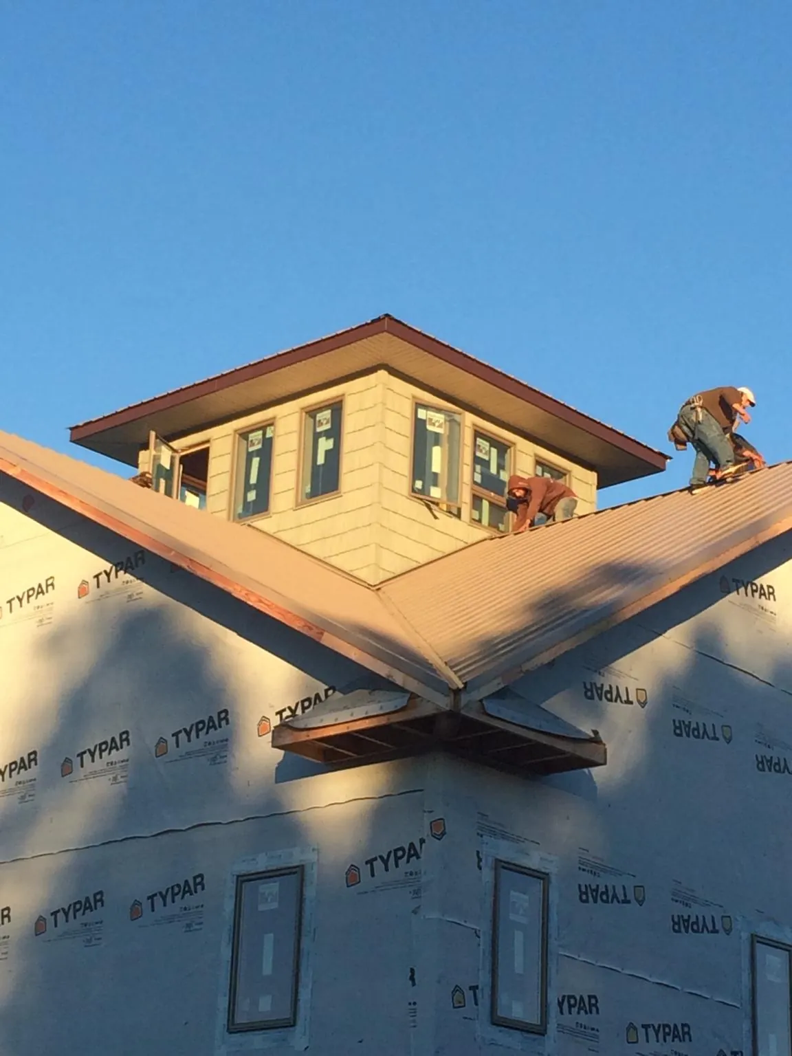 Roofers working around a rooftop cupola on a new metal roof at sunset — Roof Waterproofing in Kirkville by Roofing Brothers